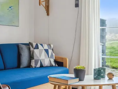 a living room with a blue couch and a table at Holiday Home Ubbe - 200m from the sea by Interhome in Lemvig