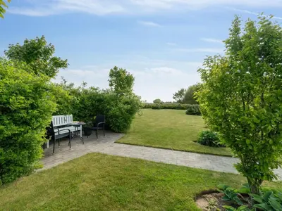 a patio with a table and chairs in a garden at Apartment Dietlinde - 1-3km to the fjord by Interhome in Thyholm