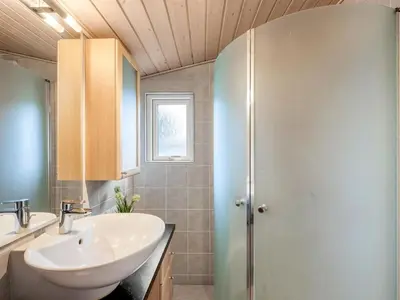 a bathroom with a white sink and a shower at Holiday Home Bosi - 100m to the fjord by Interhome in Højslev