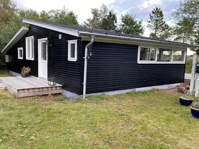 a black house with a porch and a yard at Holiday Home Bosi - 100m to the fjord by Interhome in Højslev