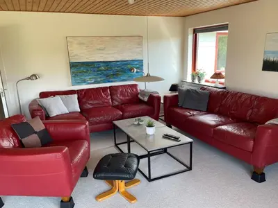 a living room with red leather couches and a table at Holiday Home Ingward - 750m from the sea by Interhome in Vestervig