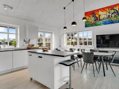 a kitchen with white cabinets and a table and chairs at Holiday Home Gizella - 500m to the fjord by Interhome in Spottrup