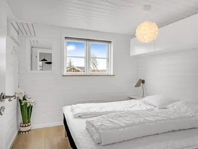 a white bedroom with two beds and a window at Holiday Home Gizella - 500m to the fjord by Interhome in Spottrup