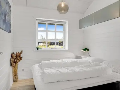 a white bedroom with a bed and a window at Holiday Home Gizella - 500m to the fjord by Interhome in Spottrup