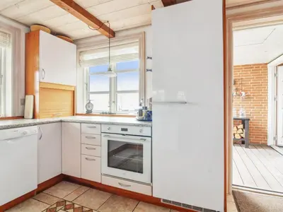 a kitchen with white cabinets and a refrigerator at Holiday Home Sander - 10m to the fjord by Interhome in Roslev