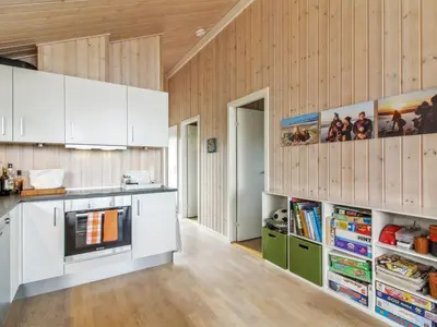 a kitchen with white cabinets and wooden walls at Holiday Home Alma - 500m from the sea by Interhome in Løkken