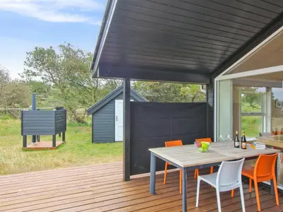 a patio with a table and chairs on a deck at Holiday Home Alma - 500m from the sea by Interhome in Løkken
