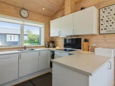 a kitchen with white cabinets and a clock on the wall at Holiday Home Sampo - 400m from the sea by Interhome in Løkken
