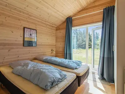 two beds in a wooden room with a window at Holiday Home Sampo - 400m from the sea by Interhome in Løkken