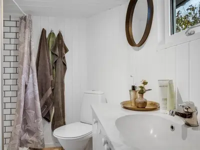 a white bathroom with a toilet and a sink at Holiday Home Kielo - 200m to the fjord by Interhome in Løgstør