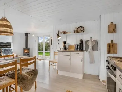 a kitchen and dining room with white walls and wooden floors at Holiday Home Kielo - 200m to the fjord by Interhome in Løgstør