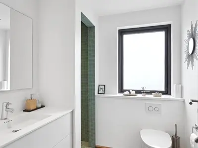 a white bathroom with a toilet and a window at Holiday Home Bena - 800m from the sea by Interhome in Blokhus