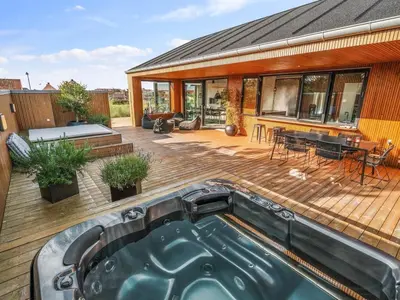 a backyard with a hot tub on a wooden deck at Holiday Home Bena - 800m from the sea by Interhome in Blokhus