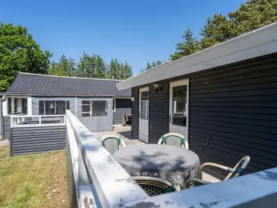 a deck with a table and chairs on a house at Holiday Home Aneline - 700m from the sea by Interhome in Saltum