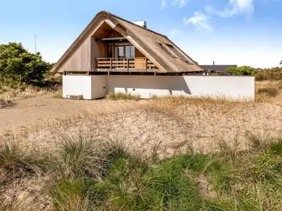a house on the beach with a thatched roof at Holiday Home Mumme - 700m from the sea by Interhome in Blokhus