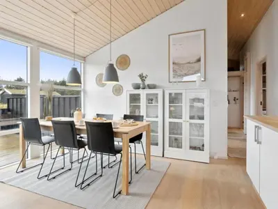 a kitchen and dining room with a wooden table and chairs at Holiday Home Sazdo - 1-1km from the sea by Interhome in Saltum