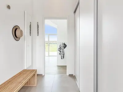 a hallway with white walls and a wooden bench at Holiday Home Egil - 1-5km from the sea by Interhome in Saltum