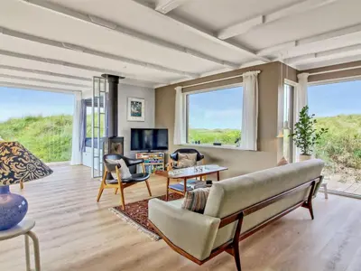 a living room with a couch and chairs and windows at Holiday Home Hoat - 300m from the sea by Interhome in Saltum