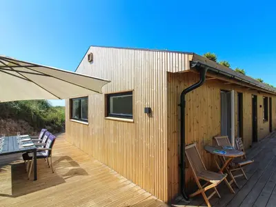 a wooden deck with chairs and a table and an umbrella at Holiday Home Hoat - 300m from the sea by Interhome in Saltum