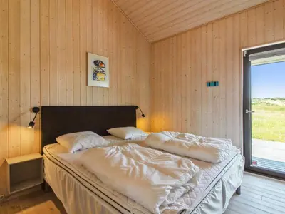 a bedroom with a bed with white sheets and a window at Holiday Home Ascan - 600m from the sea by Interhome in Løkken