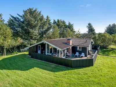 a small house with a green exterior on a field at Holiday Home Apsolon - 600m from the sea by Interhome in Løkken