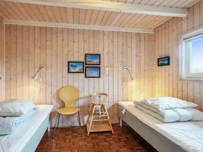 a bedroom with two beds and a chair at Holiday Home Franzisca - 700m from the sea by Interhome in Saltum