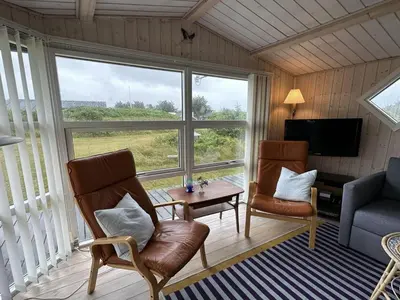a living room with two chairs and a table and a television at Holiday Home Freding - 450m from the sea by Interhome in Løkken