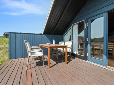 a wooden deck with a table and chairs on it at Holiday Home Henri - 500m from the sea by Interhome in Fjerritslev