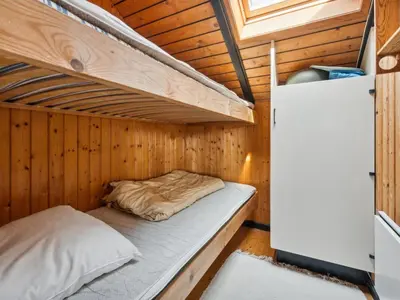 an empty bed in a wooden cabin with a window at Holiday Home Henri - 500m from the sea by Interhome in Fjerritslev