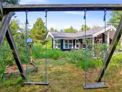 a swing in the yard of a house at Holiday Home Arlett - 950m from the sea by Interhome in Fjerritslev