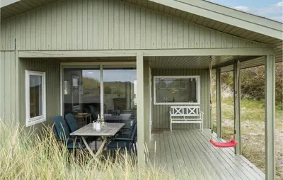 a screened in porch of a house with a table and chairs at Awesome Home In Løkken in Løkken