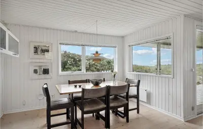 a dining room with a table and chairs and windows at Awesome Home In Løkken in Løkken