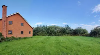 an empty field next to a brick building at Villa Vandkant in Thyholm