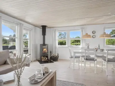 a living room with a table and a fireplace at Holiday Home Ofelia - 2-5km from the sea by Interhome in Blokhus