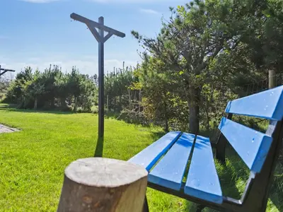 a blue bench in a park with a cross at Holiday Home Ofelia - 2-5km from the sea by Interhome in Blokhus