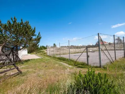 a fence in front of a road with a gate at Apartment Virpi - 1km from the sea by Interhome in Blokhus