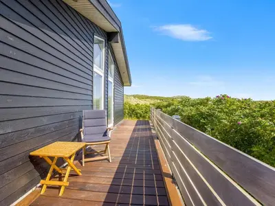a wooden deck with a table and a chair on it at Holiday Home Gebko - 150m from the sea by Interhome in Saltum