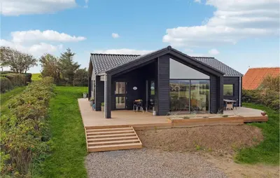 a black house with a deck and glass walls at Cozy Home In Lemvig With House Sea View in Lemvig