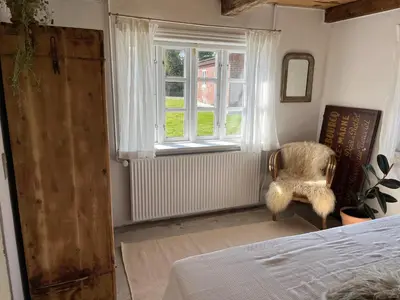 a bedroom with a bed and a window and a chair at The Beach Farm - charm, beach and stunning nature in Bedsted Thy