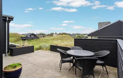 a patio with a table and chairs on a balcony at Beautiful Home In Blokhus With Wifi in Blokhus