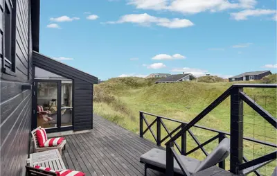 a house with a deck with chairs on it at Beautiful Home In Blokhus With Wifi in Blokhus