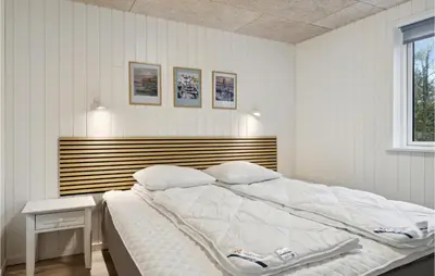 a bedroom with a large bed with a wooden headboard at 3 Bedroom Gorgeous Home In Løgstør in Løgsted