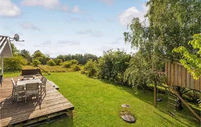 a wooden deck with a table and chairs on a lawn at Holiday Home Højslev 42 in Højslev