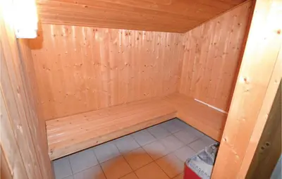 a small sauna with wooden walls and a tile floor at Holiday Home Blokhus 49 in Blokhus