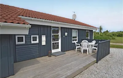 a house with a deck with a table and chairs at Holiday Home Blokhus 49 in Blokhus