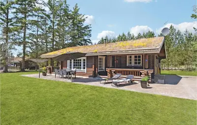 a log cabin with a patio and picnic tables at Holiday Home Blokhus 59 in Blokhus