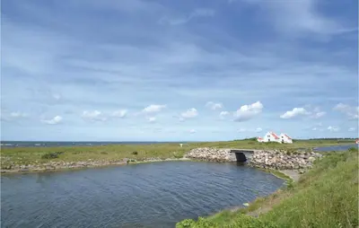 a bridge over a river with a house in the distance at Holiday Home Løgstør 53 in Løgstør
