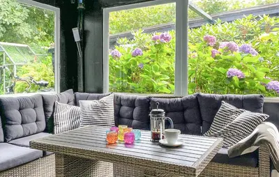 a patio with a table and a couch and flowers at 2 Bedroom Awesome Home In Vestervig in Vestervig