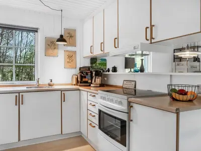 a kitchen with white cabinets and a stove top oven at Holiday Home Jobst - 600m to the fjord by Interhome in Roslev