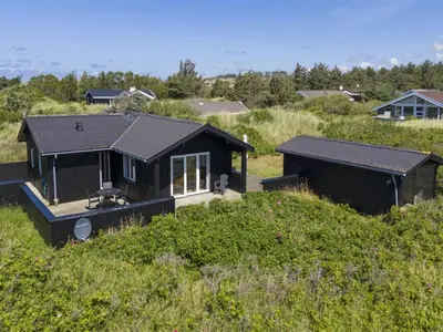 a black house sitting on top of a hill at Holiday Home Efra - 400m from the sea by Interhome in Saltum